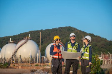 Endüstriyel Gaz Depolama Tesisindeki İnşaat Planlarını İncelemekte olan Mühendisler, Petrokimya Tesisi İnşaat Planlarını İncelemekte olan Endüstriyel Mühendisler..