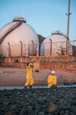 Endüstriyel gaz depolama tesisi yakınlarında su teftişi yapan mühendisler, çevresel izleme, endüstriyel güvenlik, kirlilik denetim düzenleyici uyum enerji ve petrol ve gaz endüstrisine.
