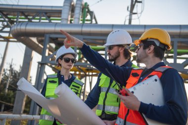 Endüstriyel Gaz Depolama Tesisindeki İnşaat Planlarını İncelemekte olan Mühendisler, Petrokimya Tesisi İnşaat Planlarını İncelemekte olan Endüstriyel Mühendisler..