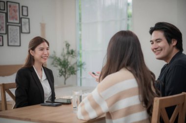 Mutlu Asyalı aile genç çiftimiz yeni ev almak için gayrimenkul alırken anahtarlarını tutuyorlar. İş finansmanı, finansal planlama için banka mevduatı.