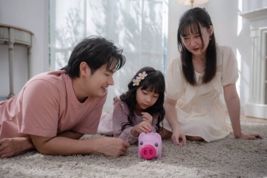 Asyalı bir aile çocuğuna evde para biriktirmeyi öğretiyor. Ailesi ve kızı domuz kumbarasına bozuk para koyuyor. Finansal eğitim, aile bağı, ebeveynlik, tasarruf ve çocukluktan kalma akıllı para alışkanlıkları.