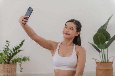 Genç Asyalı kadın antrenmandan sonra selfie çekiyor. Bu görüntü fitness için idealdir. Sosyal medya içeriği ve beden pozitifliği.