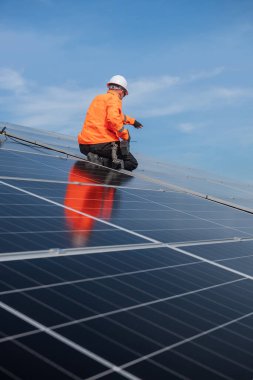 Teknisyen yeşil enerji için fabrikanın çatısına güneş panelleri kuruyor. Güvenlik teçhizatı konusunda yetenekli bir teknisyen çatıdaki bir güneş paneli tesisi üzerinde çalışıyor. Temiz enerji yenilenebilir enerji teknolojisi.