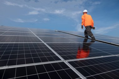 Teknisyen yeşil enerji için fabrikanın çatısına güneş panelleri kuruyor. Güvenlik teçhizatı konusunda yetenekli bir teknisyen çatıdaki bir güneş paneli tesisi üzerinde çalışıyor. Temiz enerji yenilenebilir enerji teknolojisi.