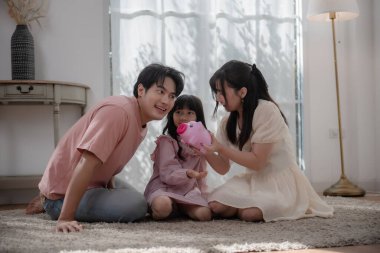 Asyalı bir aile çocuğuna evde para biriktirmeyi öğretiyor. Ailesi ve kızı domuz kumbarasına bozuk para koyuyor. Finansal eğitim, aile bağı, ebeveynlik, tasarruf ve çocukluktan kalma akıllı para alışkanlıkları.