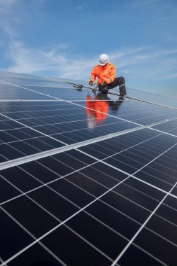 Teknisyen yeşil enerji için fabrikanın çatısına güneş panelleri kuruyor. Güvenlik teçhizatı konusunda yetenekli bir teknisyen çatıdaki bir güneş paneli tesisi üzerinde çalışıyor. Temiz enerji yenilenebilir enerji teknolojisi.