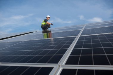 Teknisyen yeşil enerji için fabrikanın çatısına güneş panelleri kuruyor. Güvenlik teçhizatı konusunda yetenekli bir teknisyen çatıdaki bir güneş paneli tesisi üzerinde çalışıyor. Temiz enerji yenilenebilir enerji teknolojisi.