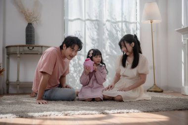 Asyalı bir aile çocuğuna evde para biriktirmeyi öğretiyor. Ailesi ve kızı domuz kumbarasına bozuk para koyuyor. Finansal eğitim, aile bağı, ebeveynlik, tasarruf ve çocukluktan kalma akıllı para alışkanlıkları.