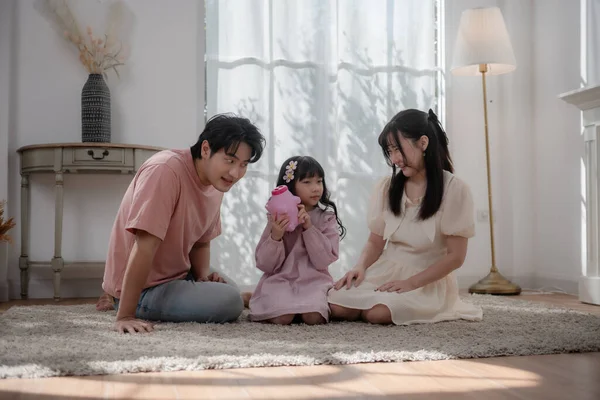 Asyalı bir aile çocuğuna evde para biriktirmeyi öğretiyor. Ailesi ve kızı domuz kumbarasına bozuk para koyuyor. Finansal eğitim, aile bağı, ebeveynlik, tasarruf ve çocukluktan kalma akıllı para alışkanlıkları.