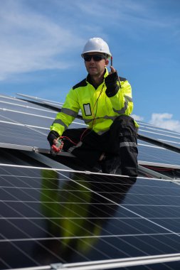 Teknisyen yeşil enerji için fabrikanın çatısına güneş panelleri kuruyor. Güvenlik teçhizatı konusunda yetenekli bir teknisyen çatıdaki bir güneş paneli tesisi üzerinde çalışıyor. Temiz enerji yenilenebilir enerji teknolojisi.