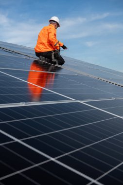 Teknisyen yeşil enerji için fabrikanın çatısına güneş panelleri kuruyor. Güvenlik teçhizatı konusunda yetenekli bir teknisyen çatıdaki bir güneş paneli tesisi üzerinde çalışıyor. Temiz enerji yenilenebilir enerji teknolojisi.