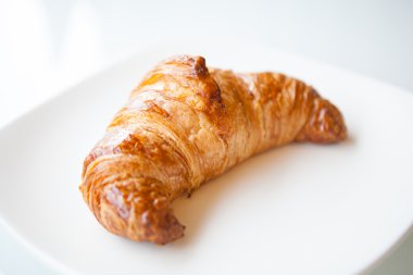 Beyaz plaka üzerinde kahverengi kruvasan