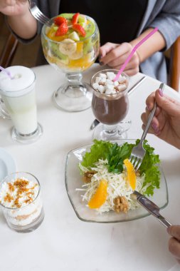 İki kadın bir kafede öğle yemeği yiyor.