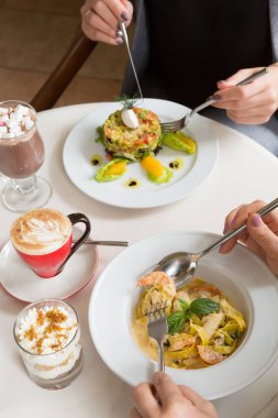 İki kadın bir kafede öğle yemeği yiyor.