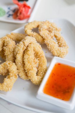 Baharatlı kırmızı sosla servis edilen kalamar halkalarında kızartılmış.