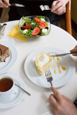 Kafede çayla tatlı yiyen bir kadın.