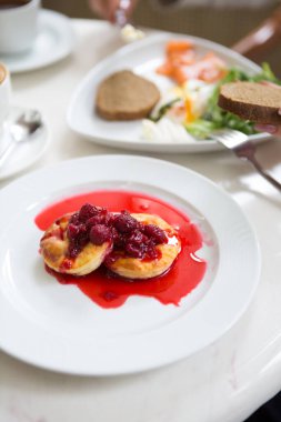 Beyaz tabakta servis edilen böğürtlenli ve kırmızı şuruplu krepler.