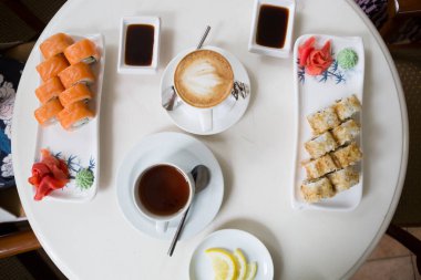 Kafe masasında içkilerle servis edilen Japon suşi dürümleri.