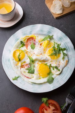 Kahvaltıda kızarmış yumurta, domates ve roka.