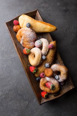 Farklı türde çörekler, ahşap tepside sunuluyor.