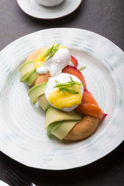 Kahvaltıda avokado, somon ve kızarmış yumurta servis edilir.