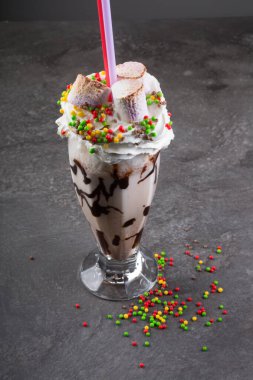 Koyu arkaplanda kremayla süslenmiş çılgın milkshake.