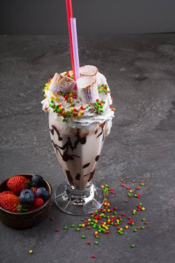 Koyu arkaplanda kremayla süslenmiş çılgın milkshake.