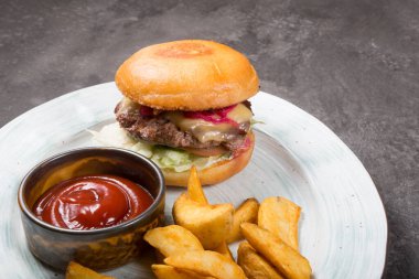 Fırında patates ve ketçap sosuyla servis edilen klasik hamburger.