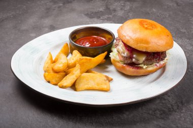 Fırında patates ve ketçap sosuyla servis edilen klasik hamburger.