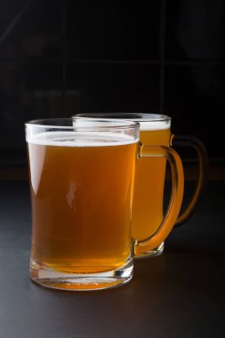 Siyah arka planda servis edilen bir bardak bira.