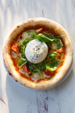 Kafe masasında Napoli pizzası üzerine Buratta peyniri.