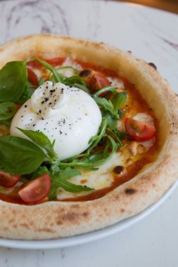 Kafe masasında Napoli pizzası üzerine Buratta peyniri.