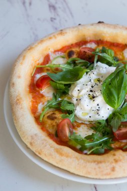 Kafe masasında Napoli pizzası üzerine Buratta peyniri.