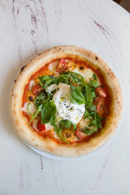 Kafe masasında Napoli pizzası üzerine Buratta peyniri.