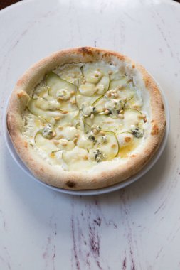 Kafe masasında armut ve peynirli Napoli pizzası.