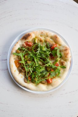 Beyaz mermer bir masada yuvarlak pişmiş Napoli pizzası.