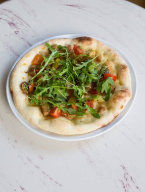 Beyaz mermer bir masada yuvarlak pişmiş Napoli pizzası.