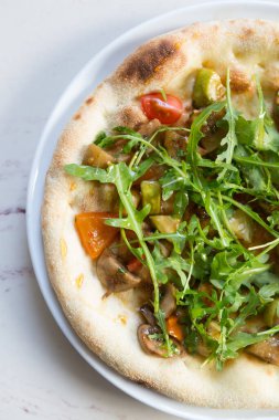 Beyaz mermer bir masada yuvarlak pişmiş Napoli pizzası.