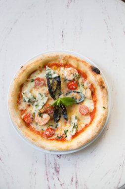 Bütün Napoli deniz ürünleri pizzası mermer bir kafe masasında servis edilir.