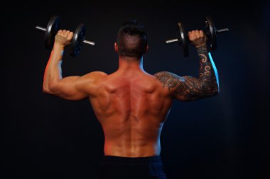 Kaslı adam arkasında dumbbells ile