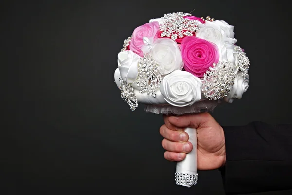 Hand holds wedding bouquet for bride