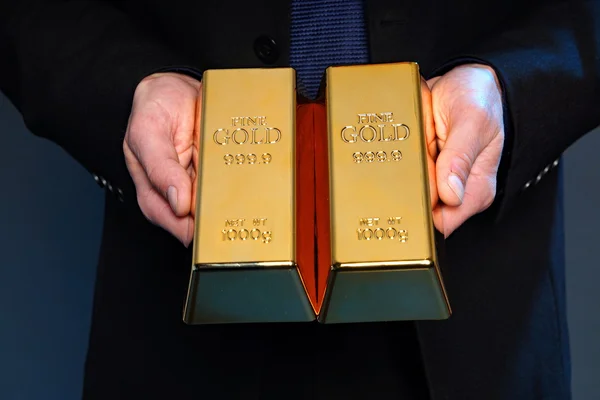 Hands holds gold bricks — Stock Photo, Image