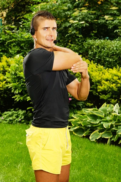 Aerobics male coach stretching in garden — Stock Photo, Image