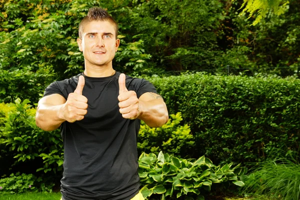 Muscular man gesturing thumbs up sign — Stock Photo, Image