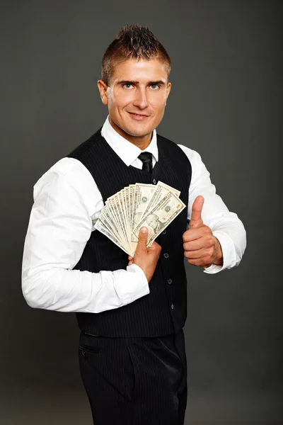 El hombre posa con dinero y señala con el pulgar hacia arriba —  Fotos de Stock