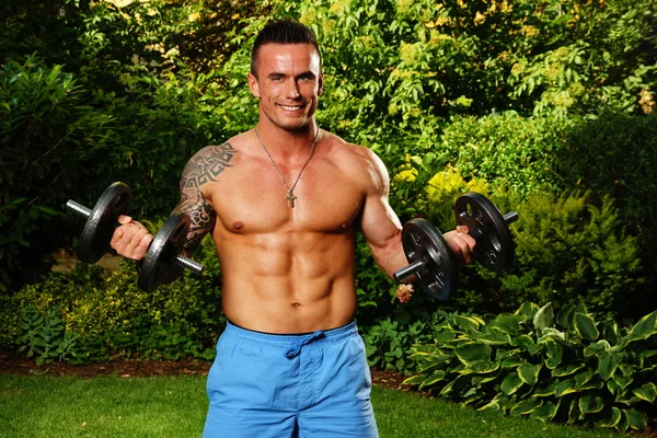 Young man exercisess with dumbells — Stock Photo, Image