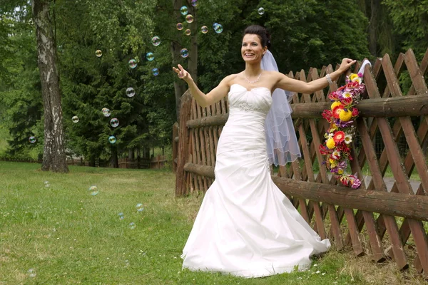 Bride catches the bubbles from the bubble blower — Stock Photo, Image