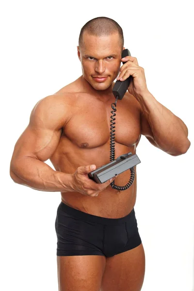 Muscular man speaks into telephone — Stock Photo, Image