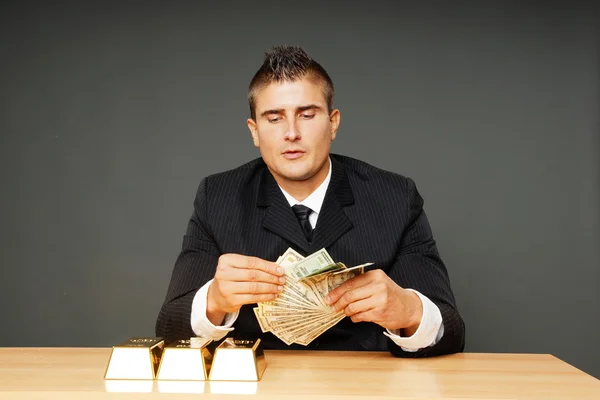 Hombre con ladrillos de oro cuenta el dinero —  Fotos de Stock