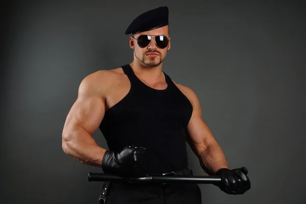 Soldado muscular posa com bastão — Fotografia de Stock